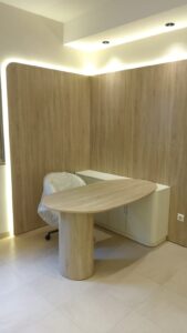 Escritório com painéis de madeira e mesa oval; móveis planejados e produzidos pela Creare Ambientes.
